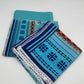 Two folded fabric pieces with blue and patterned designs on a white background