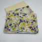 Stack of floral fabric with purple and green flowers on a white background