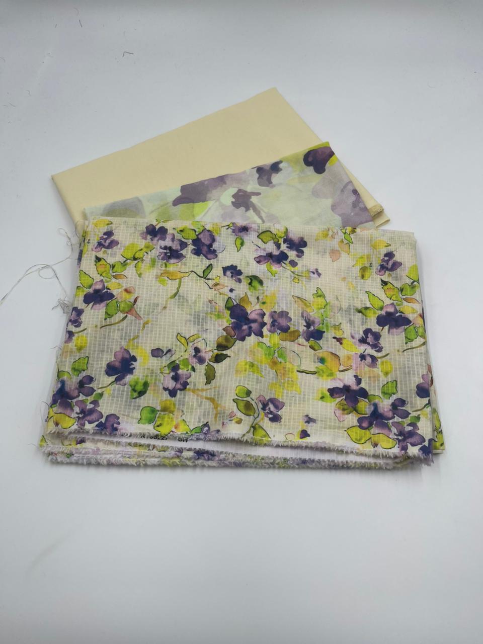 Stack of floral fabric with purple and green flowers on a white background