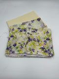 Stack of floral fabric with purple and green flowers on a white background